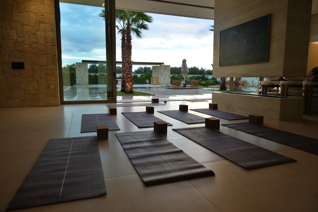 Serene yoga studio with mats arranged facing pool and palm trees at dusk